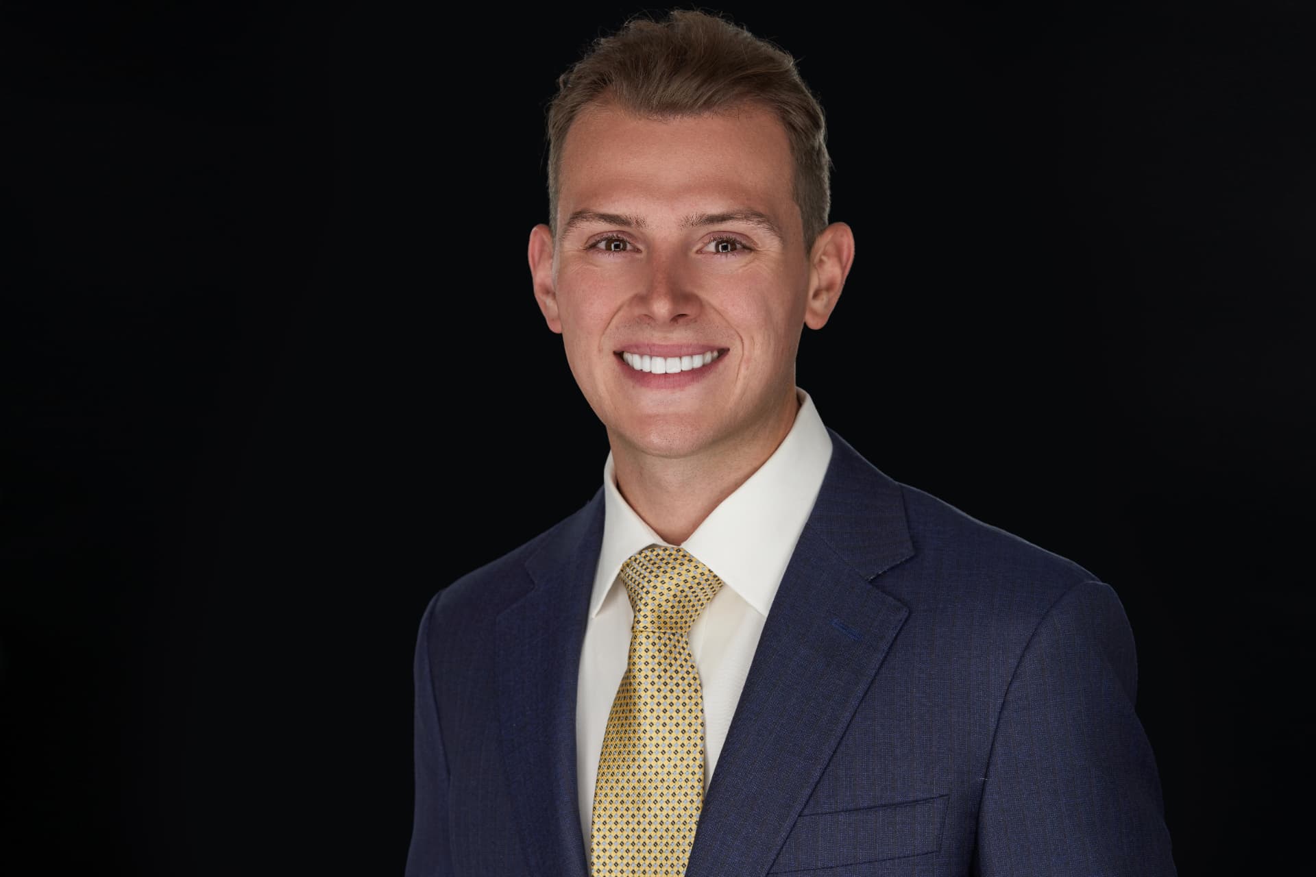 Portrait of Cole DeFranco in a dark suit against a dark background